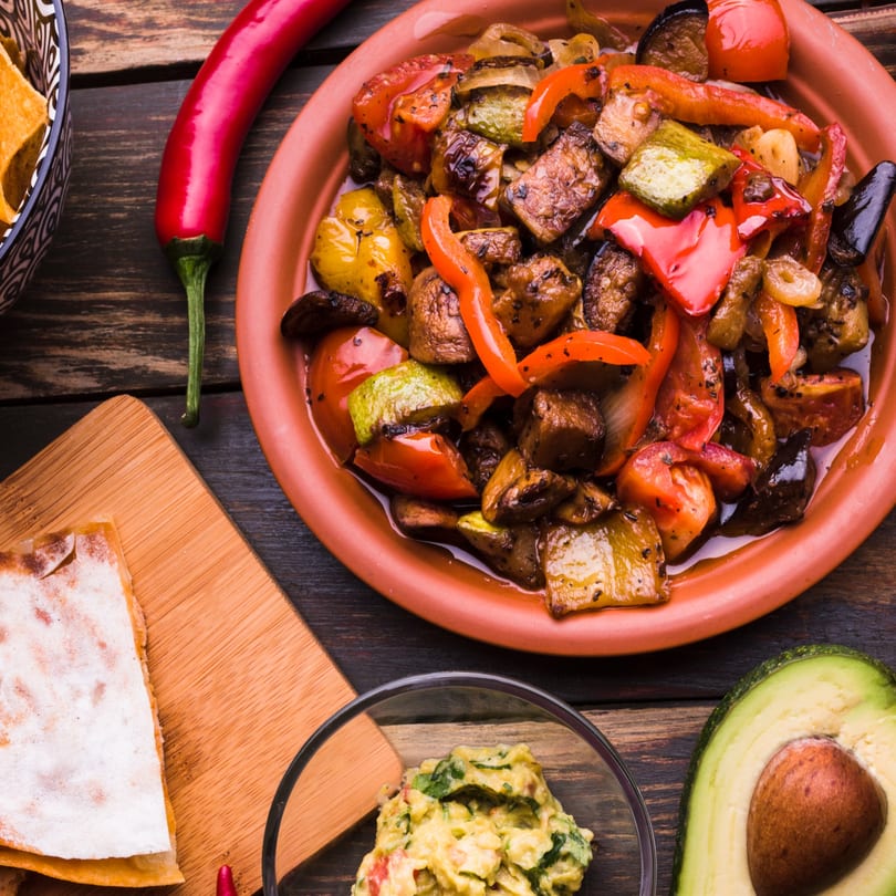 Maestros’s Mexican grill's colorful fajita vegetables, guacamole, quesadilla, and tortilla chips on a wooden table.