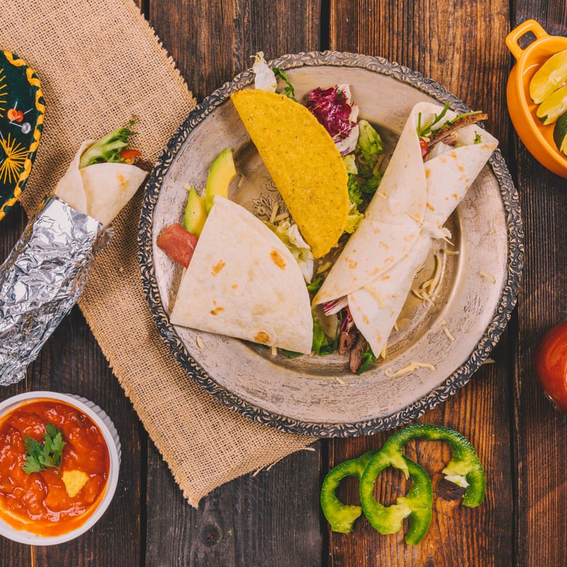 Maestros’s Mexican grill tacos and burritos with salsa and lime on a rustic wooden table.
